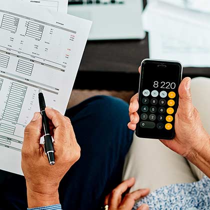 Mature hands holding paperwork and calculator.