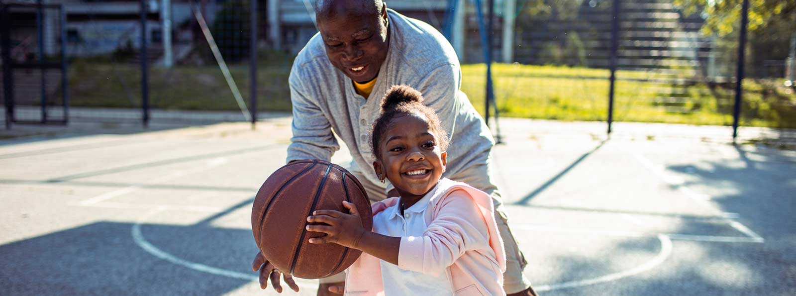 Girl and her grandpa playing basketball.