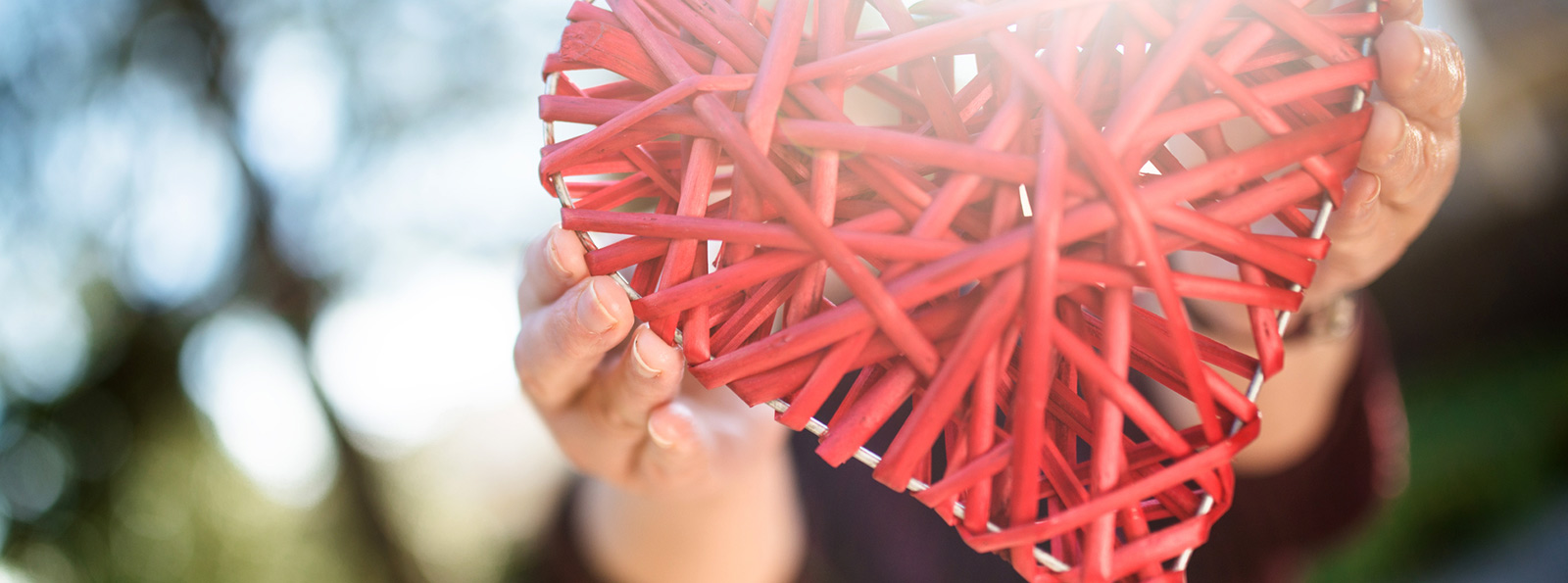 two hands holding a red wicker heart