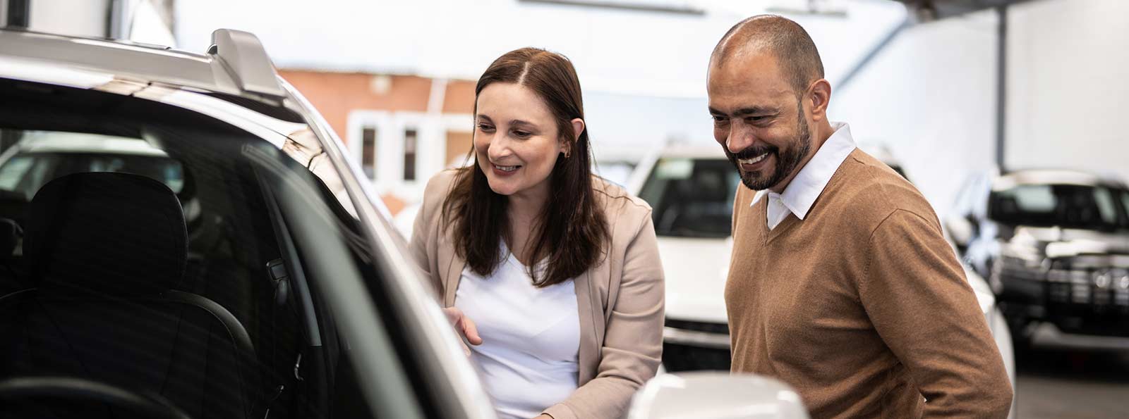 Couple looking at car in lot.